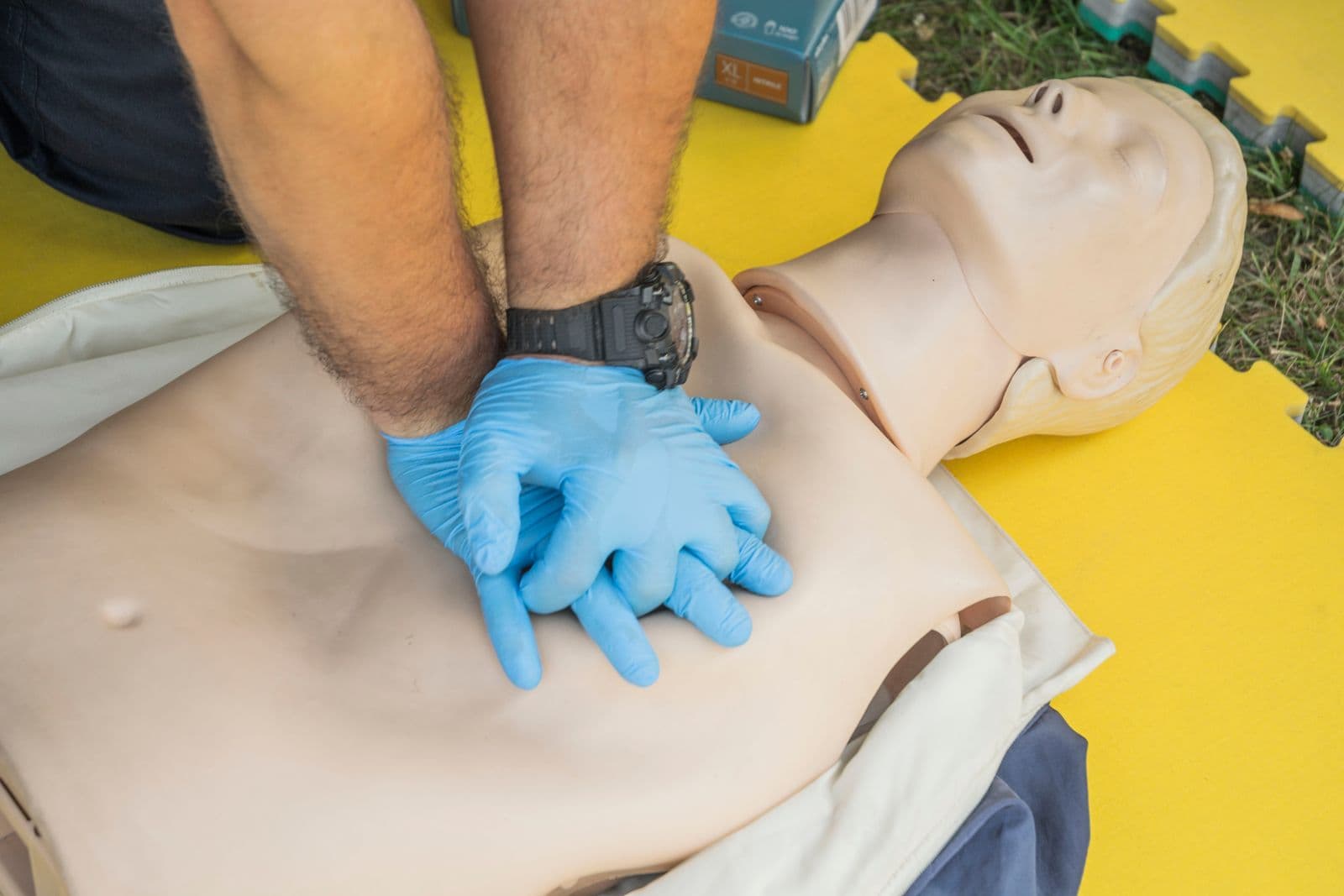 Hands practising CPR compressions on a training manikin