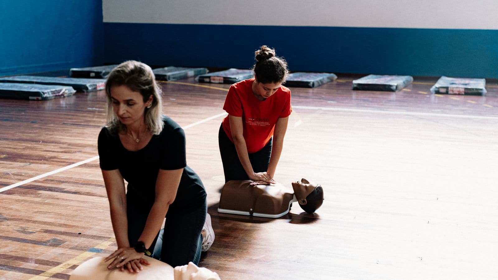 Learners practising CPR on manikins during a first aid class
